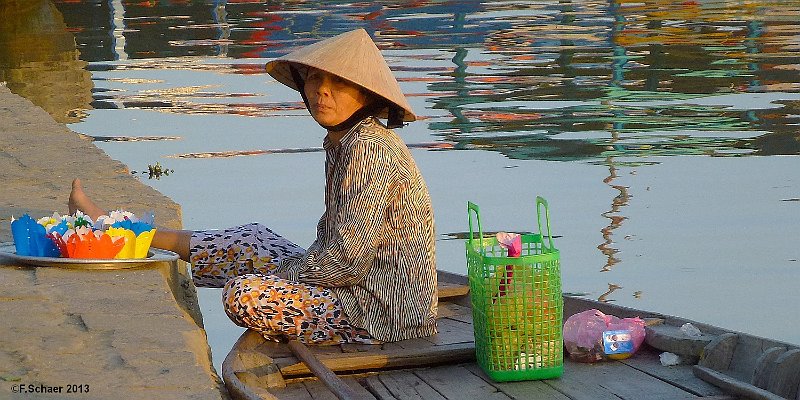 Horizonte 165.jpg - a vietnamese lady in her boat, waiting for customers.It's a lucky talisman to buy one of the paper-boats with a ignitedtea-light inside and let it swim down the river.The woman keep herboat with her foot against drifting with the current.I made this picture in the harbour of the beautiful restored old cityof Hoi An along the coast of the South China Sea   click here for Google Maps View   Position: N15°52'35" E108°19'42", about on sealevel Camera: Panasonic TZ20, date: 17/01/2013, 17:10 local time