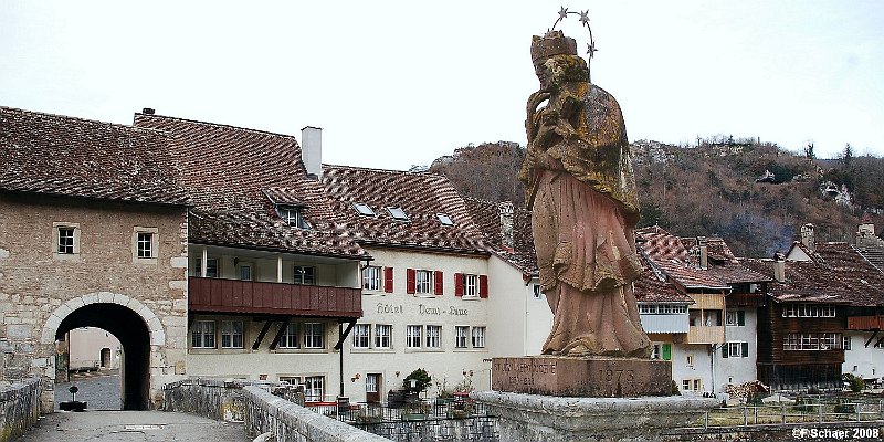 Horizonte 261.jpg - shows the riverfront of the medevial village of St.Ursanne in thenorthwest of Switzerland. The statue in the middle of the bridge represents the "Saints of the Bridges", Johannes Nepomuk (1345-1392),living in Prague.   click here for Google Maps View   Position (Google Earth): N47°21'50,60"/E 07°09'17", elev.435m/1415ft Camera: Nikon D50, with 28mm PC-Nikkor, date: 09/03/2008