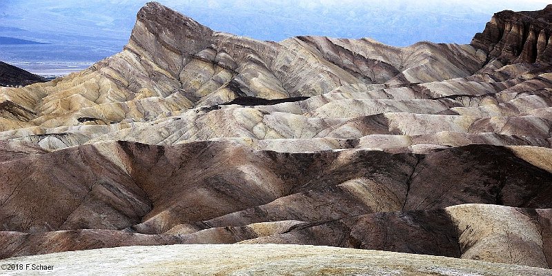 Horizonte 333.jpg - a great view from Zabriskie-Viewpoint withinDeath Valley National Park, overlooking a colorful andrugged landscape with mudhills and deep gullies between.In a distance the bottom of Death Valley, mostly belowSea-level.Position: N 36°25'12"/ W 116°48'44", about 200m above SL.Camera: Nikon D50, date: 21/10/2018, 10:28am