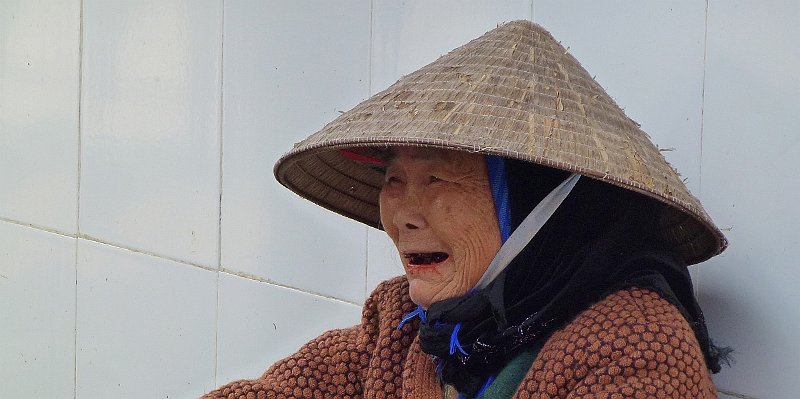 Horizonte 85.jpg - an older cambodian lady sat beside her market-stall near the Royal Palace in Phnom Penh, the capital ob Cambodia. Her teeths are gone and her mouth shows red, the typical result of lifelong Betel-chewing, usually and widespread in south-eastern Asia.    click here for Google Maps View   Position: N11°33'59" E104°55'49", elev.18m/60ft Camera: Lumix TZ20, date: 11/02/2013, 12:41 local